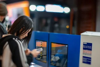 Woman Using Blue Ticket Machine at Night Station - free people & portraits wallpaper 5568×3712