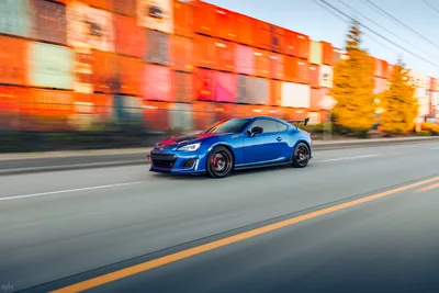 Blue Sports Car Racing Past Orange Building - free cars & vehicles wallpaper 4472×2982