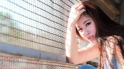 Young Woman Posing by Chain-Link Fence in Sunlight - free people & portraits wallpaper 5760×3240