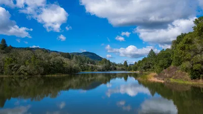 Serene River Landscape With Forested Mountains and Blue Sky - free wallpaper 6144×3456