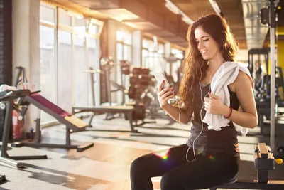 Woman at Gym Checking Phone with Earbuds - free people & portraits wallpaper 2121×1414