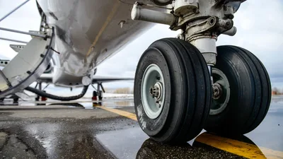 Aircraft Landing Gear Close-Up on Wet Runway - free wallpaper 6000×3375