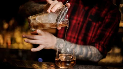 Bartender Pouring Whiskey Into Glass With Ice - free wallpaper 4256×2395