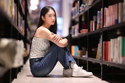 Young Woman Sitting in Library Between Bookshelves - free people & portraits wallpaper 6144×4096