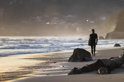 Surfer Walking on Beach at Dusk with Coastal Rocks - free people & portraits wallpaper 5918×3945