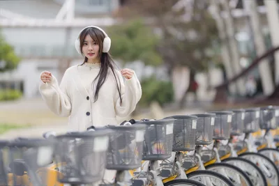 Woman in White Coat with Earmuffs by Bike Rack - free people & portraits wallpaper 5120×3418