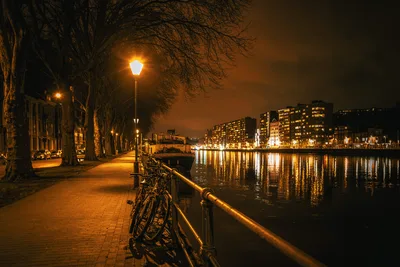 Nighttime Riverside Promenade with Bicycles and City Lights - free city & urban wallpaper 7927×5285