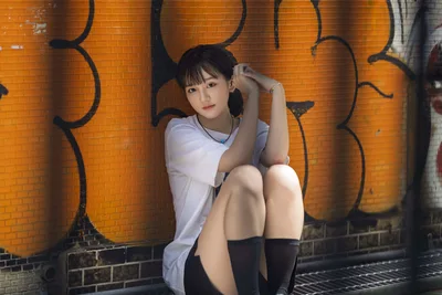 Young Woman Posing Against Orange Brick Wall Mural - free wallpaper 5120×3418