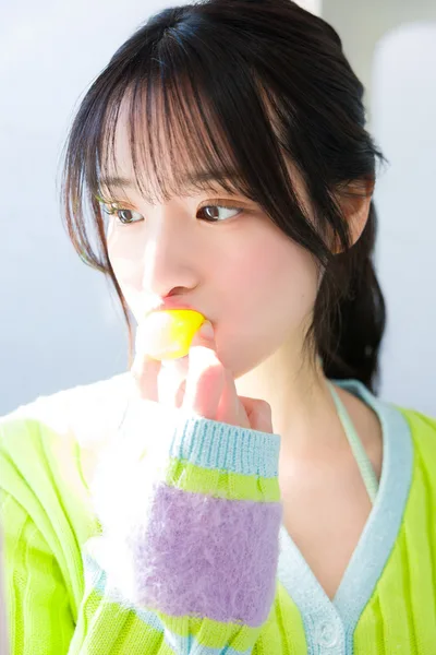 Young Woman Eating Yellow Lollipop in Colorful Sweater - free people & portraits wallpaper 2048×3073