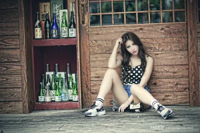 Young Woman Posing Against Wooden Building with Sake Bottles - free wallpaper 5760×3840