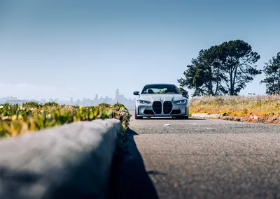 White BMW M4 on Coastal Road with City Skyline - free cars & vehicles wallpaper 6206×4419