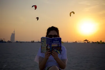 Tourist Reading Dubai Travel Guide at Sunset Beach - free people & portraits wallpaper 8284×5523
