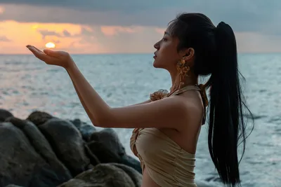 Woman Holding Sunset Over Ocean at Rocky Shoreline - free wallpaper 5775×3850