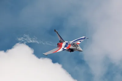 Red and Blue Fighter Jet Banking Through Clouds - free wallpaper 5472×3648