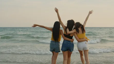 Four Young Women Celebrating at the Beach with Arms Raised - free wallpaper 4000×2250
