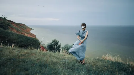 Woman in Blue Dress Overlooking Coastal Cliffs - free wallpaper 2560×1440