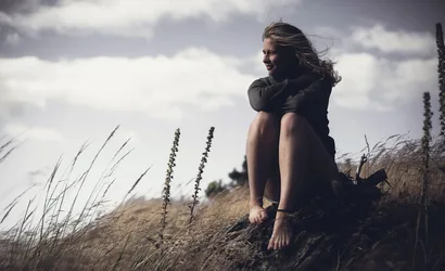 Woman Sitting on Coastal Dunes with Ocean View - free wallpaper 2047×1247