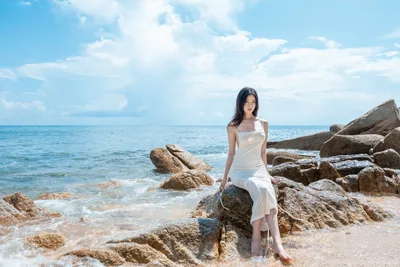 Woman in White Dress on Rocky Beach by Sea - free wallpaper 4096×2731