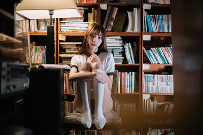Woman Sitting in Library With Bookshelves - free wallpaper 3000×1992