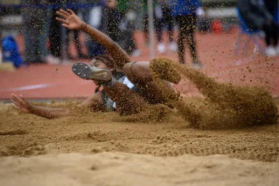 Long Jump Athlete Landing in Sand Pit - free sports wallpaper 5120×3413