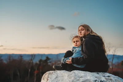 Woman and Child Sitting on Rock Overlooking Valley - free wallpaper 6144×4096