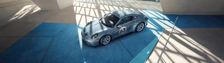Porsche 911 Sports Car in Sunlit Blue Garage - free wallpaper 5120×1440