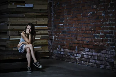 Woman Sitting on Wooden Bench Against Brick Wall - free wallpaper 1920×1281