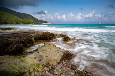 Tropical Beach with Rocky Shoreline and Sailboat - free nature wallpaper 4898×3265