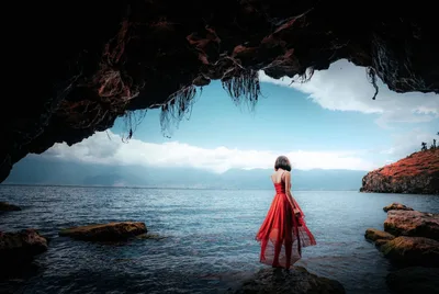 Woman in Red Dress at Seaside Cave Overlooking Mountain Lake - free people & portraits wallpaper 7680×5142